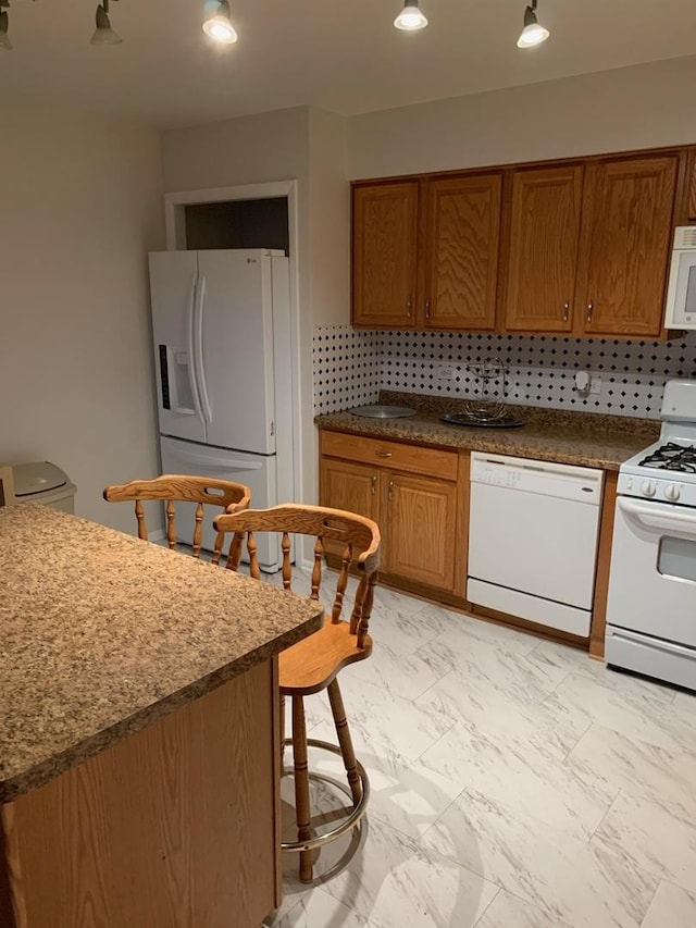 kitchen featuring white appliances, brown cabinets, marble finish floor, and decorative backsplash