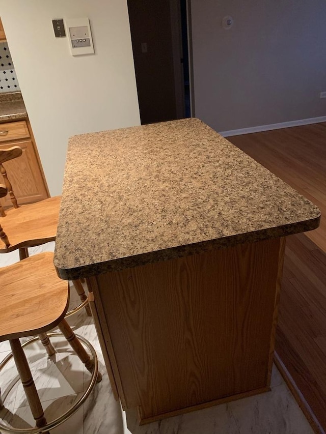 kitchen with baseboards, wood finished floors, and a center island