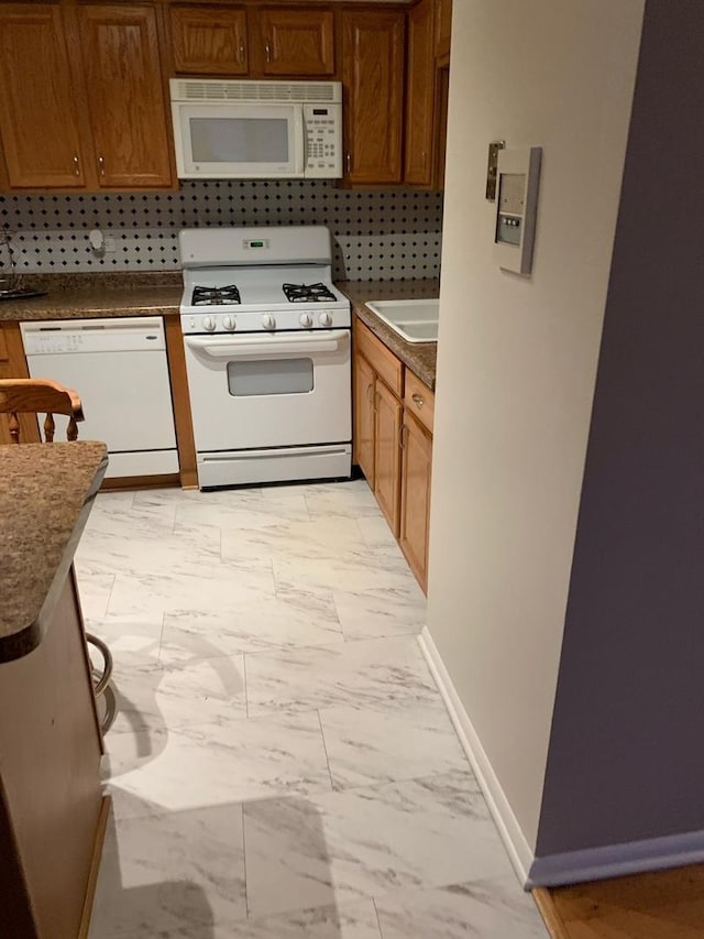 kitchen featuring white appliances, a sink, marble finish floor, tasteful backsplash, and dark countertops