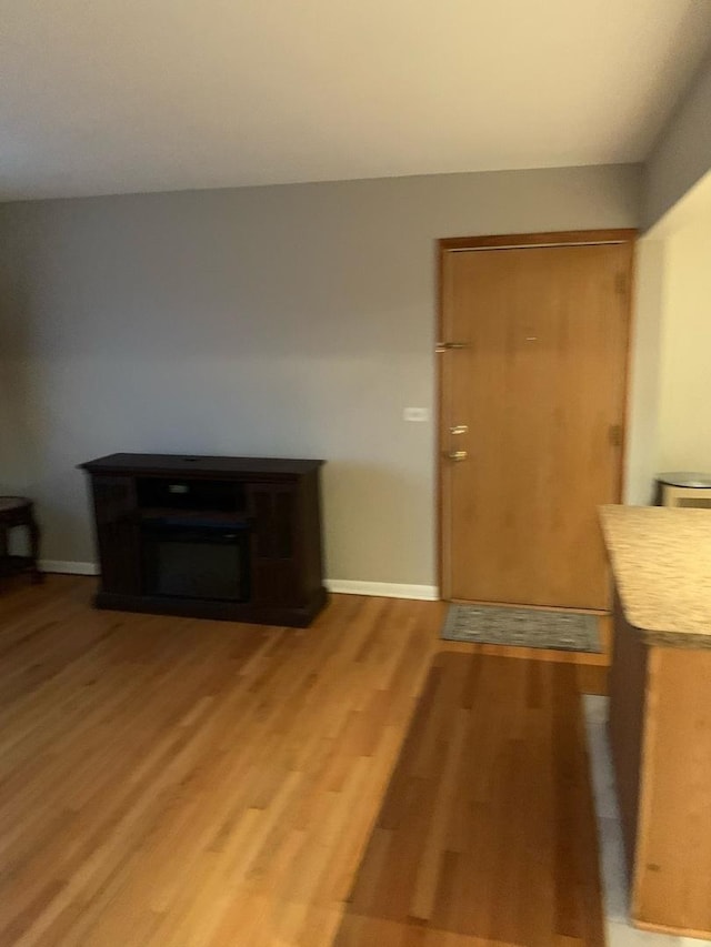 foyer entrance featuring a fireplace, light wood-style flooring, and baseboards