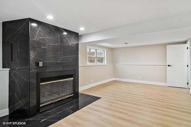 unfurnished living room featuring recessed lighting, a fireplace, wood finished floors, and baseboards