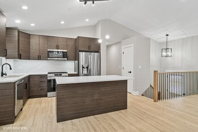 kitchen featuring a center island, light countertops, appliances with stainless steel finishes, dark brown cabinets, and modern cabinets