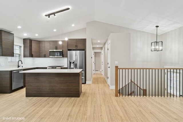 kitchen with a center island, stainless steel appliances, light countertops, dark brown cabinetry, and light wood-type flooring