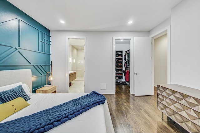 bedroom featuring a walk in closet, a closet, recessed lighting, and wood finished floors