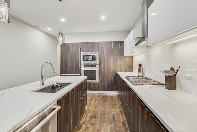 kitchen with appliances with stainless steel finishes, a sink, wall chimney exhaust hood, and modern cabinets