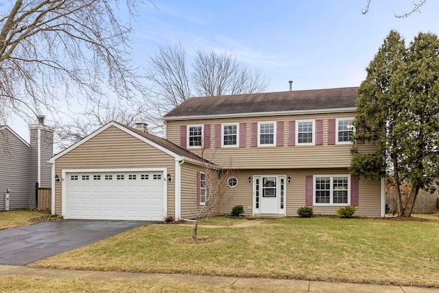 colonial home with a garage, aphalt driveway, and a front yard