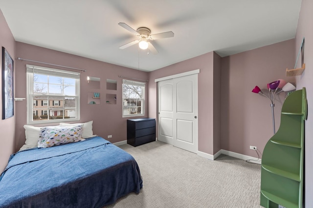 carpeted bedroom featuring a ceiling fan, a closet, multiple windows, and baseboards