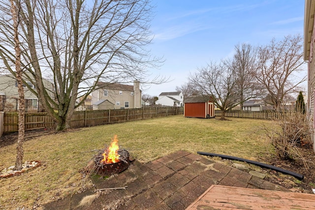 view of yard featuring a fire pit, a storage unit, an outdoor structure, and a fenced backyard