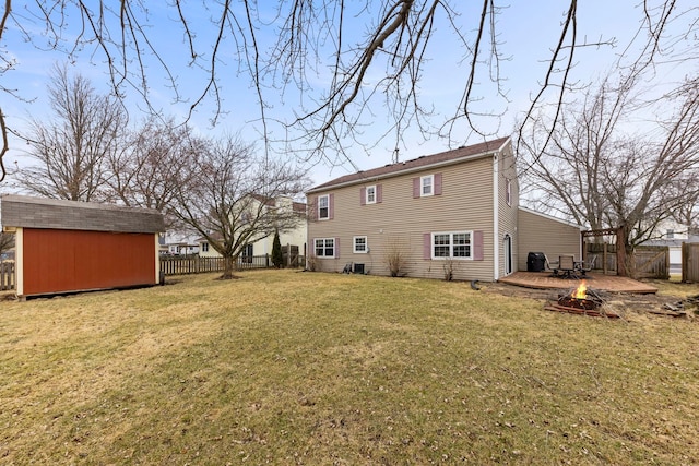 back of property featuring a storage unit, a lawn, an outdoor fire pit, a fenced backyard, and an outdoor structure