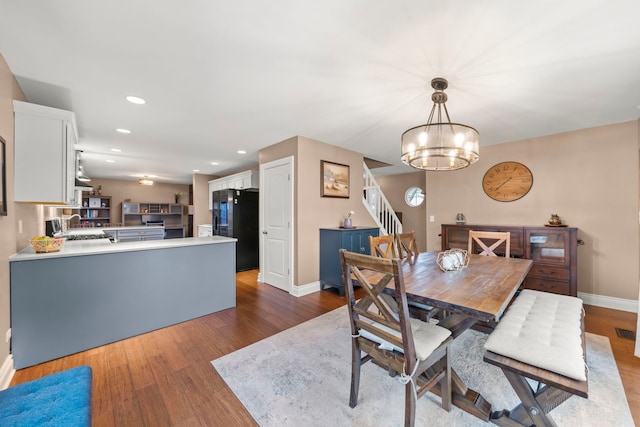 dining room featuring a notable chandelier, stairs, baseboards, and wood finished floors