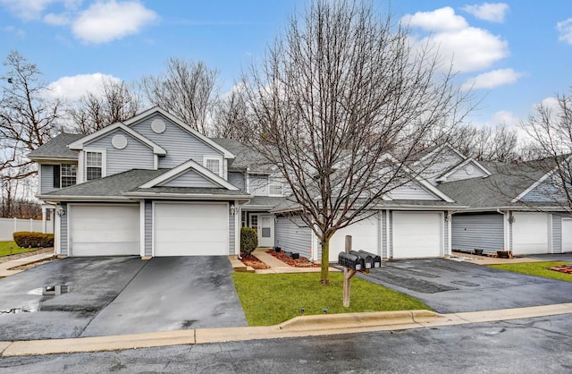 traditional home with a garage, driveway, a shingled roof, and fence