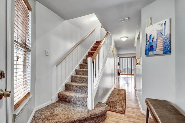 staircase featuring wood finished floors and baseboards