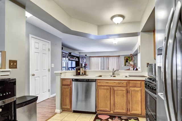 kitchen with light tile patterned floors, brown cabinets, stainless steel appliances, light countertops, and a sink