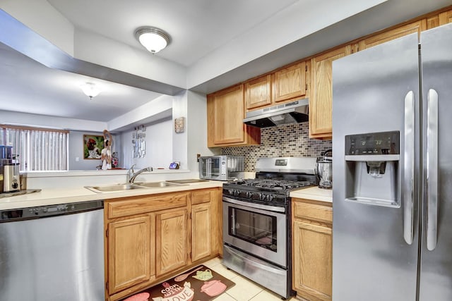 kitchen featuring stainless steel appliances, light countertops, decorative backsplash, a sink, and under cabinet range hood