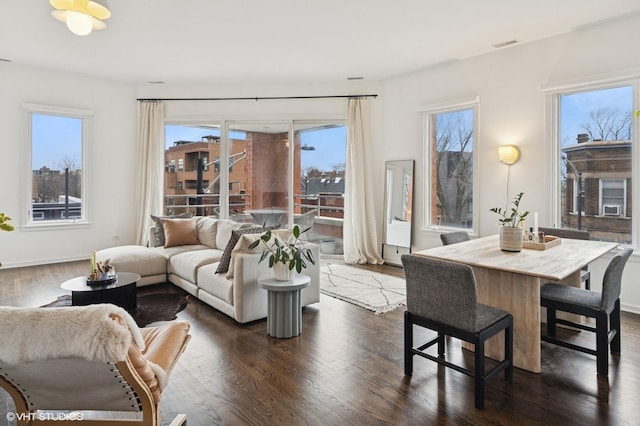 living room featuring a healthy amount of sunlight, baseboards, and dark wood finished floors