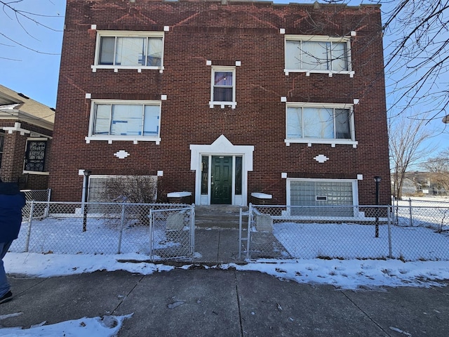 view of front of property featuring brick siding, a fenced front yard, and a gate