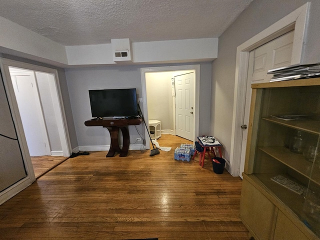 interior space featuring a textured ceiling, wood-type flooring, and visible vents