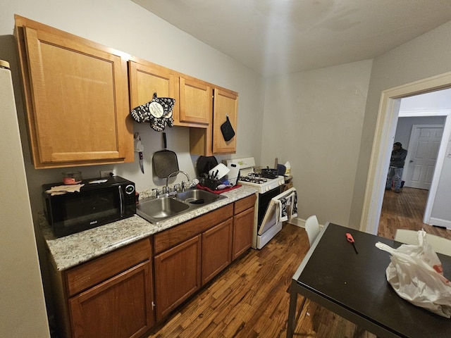 kitchen featuring white range with gas cooktop, dark wood finished floors, light countertops, black microwave, and a sink