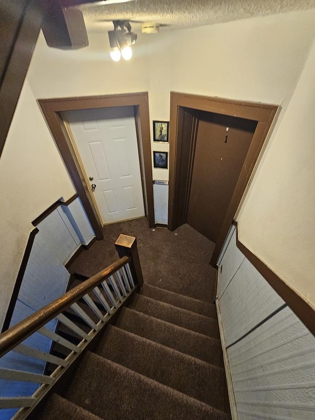 stairs with a textured ceiling and carpet flooring