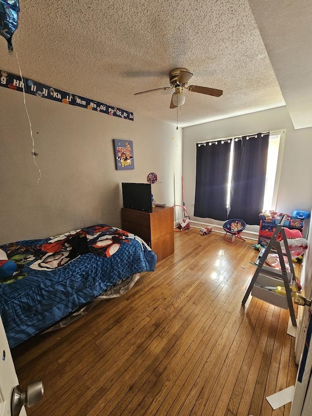 bedroom with ceiling fan, a textured ceiling, and hardwood / wood-style floors