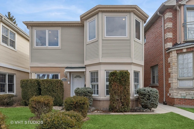 townhome / multi-family property with brick siding and a front yard