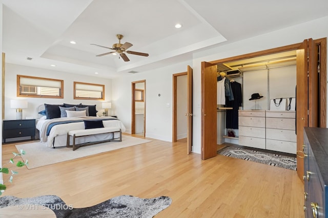 bedroom with light wood finished floors, recessed lighting, and a tray ceiling