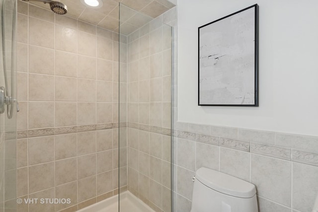 bathroom featuring a tile shower, recessed lighting, toilet, and tile walls