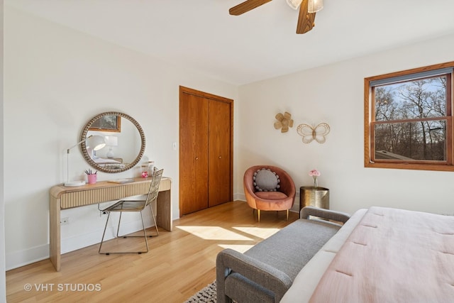 bedroom with a ceiling fan, wood finished floors, baseboards, and a closet