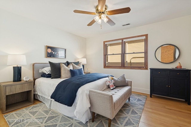 bedroom with ceiling fan, visible vents, baseboards, and light wood-style flooring