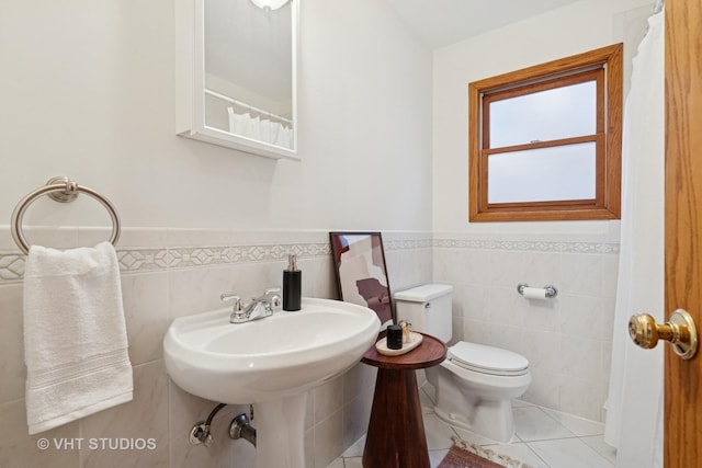 bathroom with tile patterned floors, toilet, tile walls, and a wainscoted wall