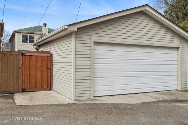 detached garage with a gate and fence