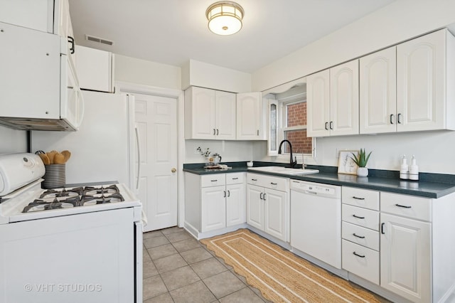 kitchen featuring white appliances, light tile patterned flooring, a sink, white cabinetry, and dark countertops