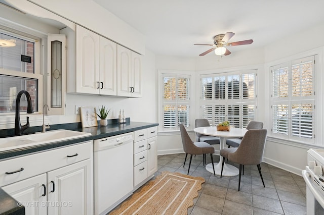 kitchen featuring white appliances, baseboards, a sink, white cabinetry, and dark countertops