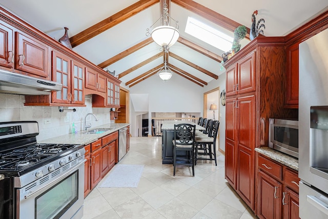 kitchen featuring light stone countertops, under cabinet range hood, decorative backsplash, appliances with stainless steel finishes, and a sink