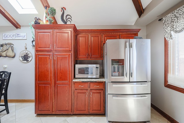 kitchen with lofted ceiling with skylight, white microwave, stainless steel refrigerator with ice dispenser, and baseboards