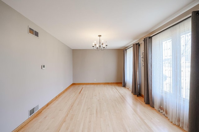 unfurnished room with visible vents, baseboards, a chandelier, and light wood finished floors