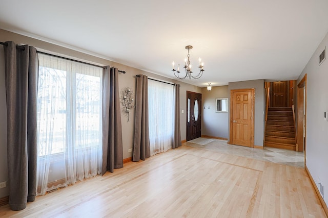 interior space with visible vents, a notable chandelier, light wood-style floors, baseboards, and stairs