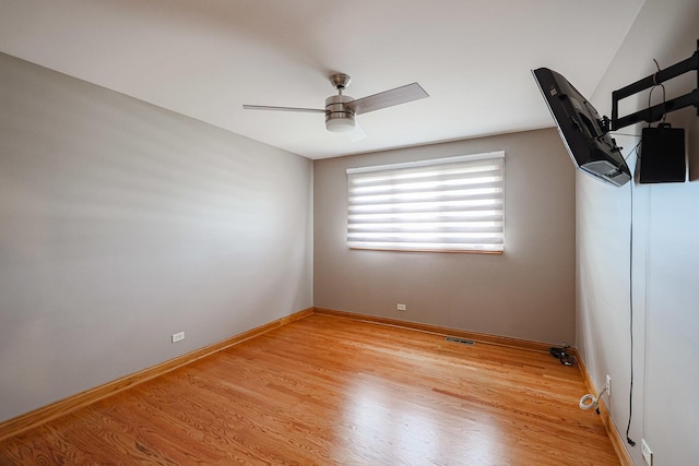 spare room featuring baseboards, light wood-style floors, and a ceiling fan