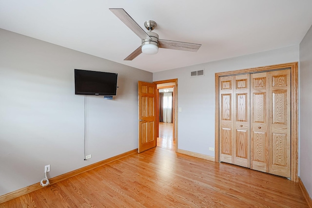 unfurnished bedroom featuring a ceiling fan, visible vents, light wood-type flooring, and baseboards