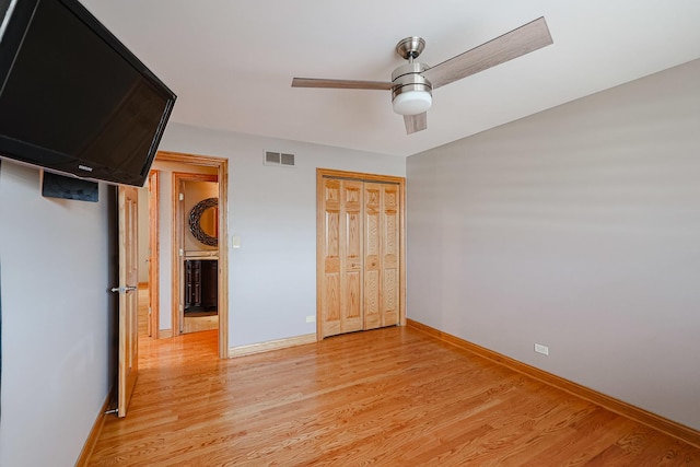 unfurnished bedroom featuring baseboards, visible vents, light wood-style flooring, ceiling fan, and a closet