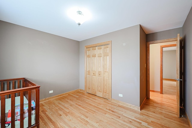 unfurnished bedroom featuring baseboards, light wood-type flooring, and a closet