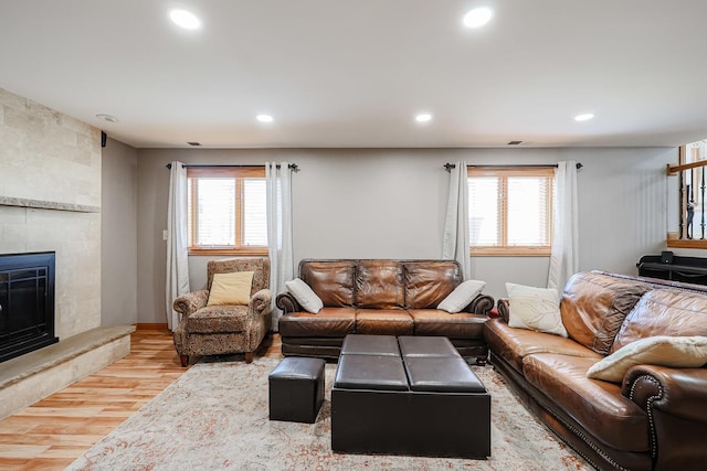 living room featuring recessed lighting, plenty of natural light, wood finished floors, and a fireplace