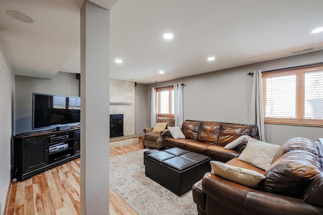 living room featuring visible vents, recessed lighting, a large fireplace, and light wood-style floors