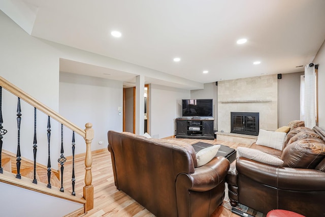 living area with stairway, baseboards, recessed lighting, light wood-type flooring, and a large fireplace