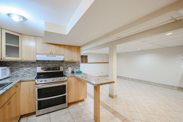 kitchen with light tile patterned floors, double oven range, light brown cabinets, decorative backsplash, and under cabinet range hood