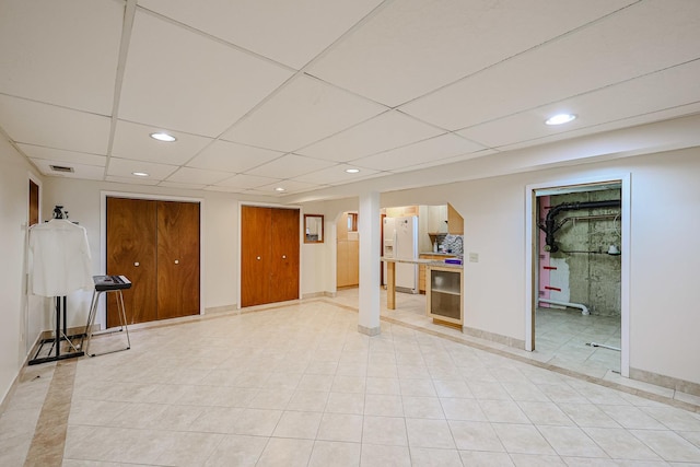 finished basement featuring recessed lighting, visible vents, baseboards, and white fridge with ice dispenser