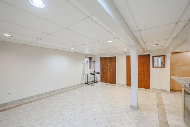 finished basement with recessed lighting, a drop ceiling, baseboards, and light tile patterned floors