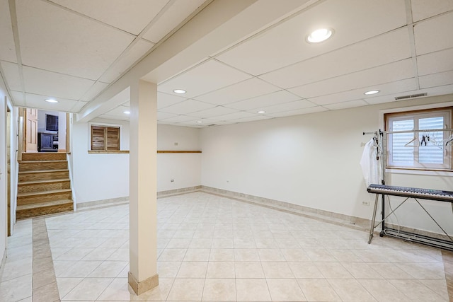 below grade area with stairs, visible vents, baseboards, and a drop ceiling