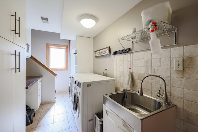 laundry room with light tile patterned floors, visible vents, cabinet space, a sink, and washing machine and dryer