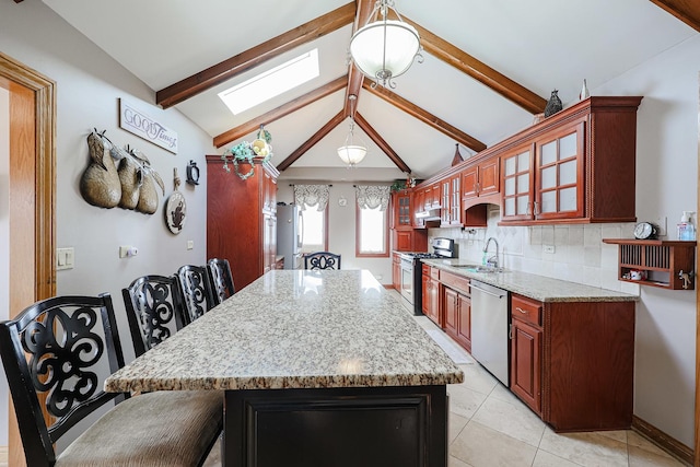 kitchen with glass insert cabinets, decorative backsplash, vaulted ceiling with skylight, stainless steel appliances, and a sink